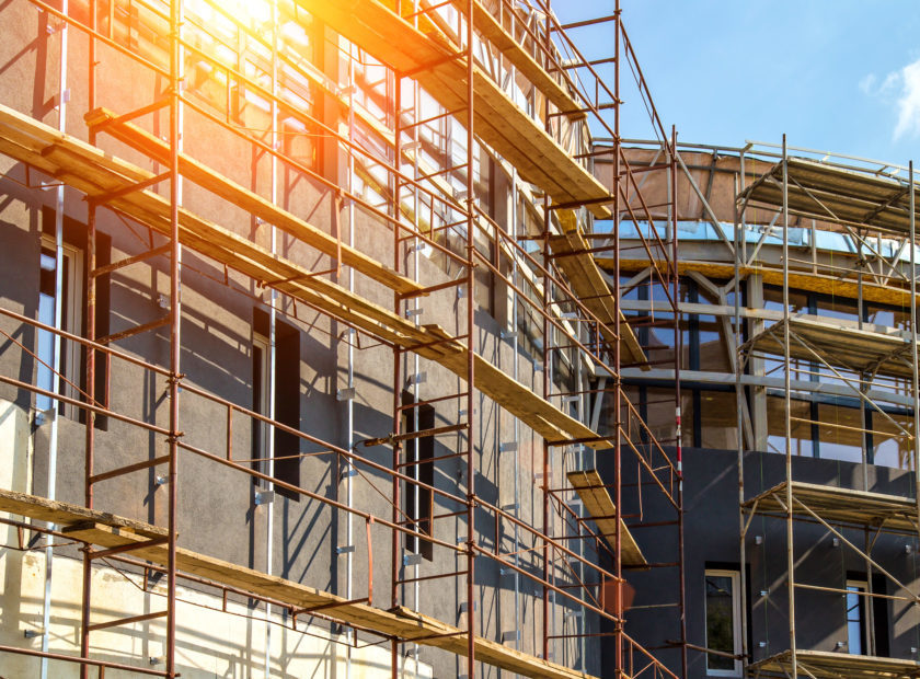 Extensive scaffolding providing platforms for work in progress on a new apartment block,Tall building under construction with scaffolds,Construction Site of New Building