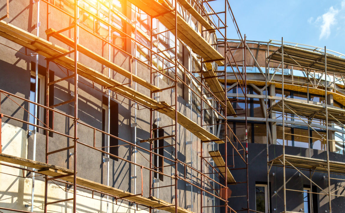 Extensive scaffolding providing platforms for work in progress on a new apartment block,Tall building under construction with scaffolds,Construction Site of New Building